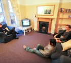 Friends talking in plymouth student house lounge on sofas.