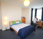 Plymouth university tenant at work at desk in double bedroom student house.
